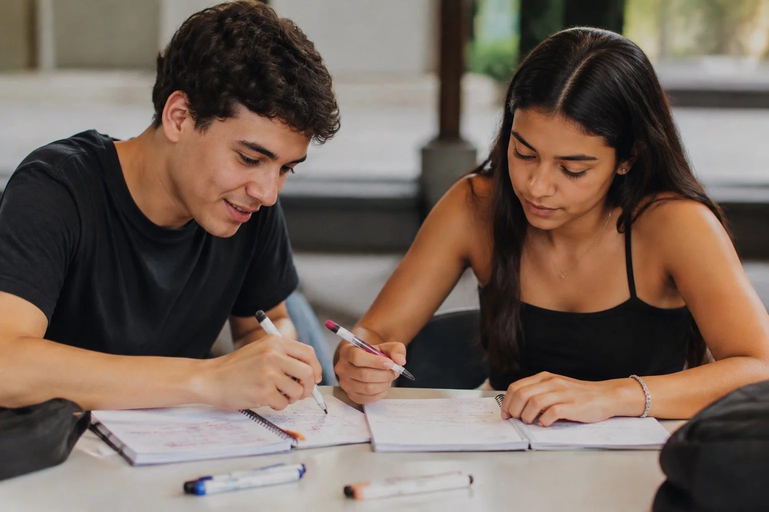 Dois estudantes preparando um debate com cadernos e marcadores